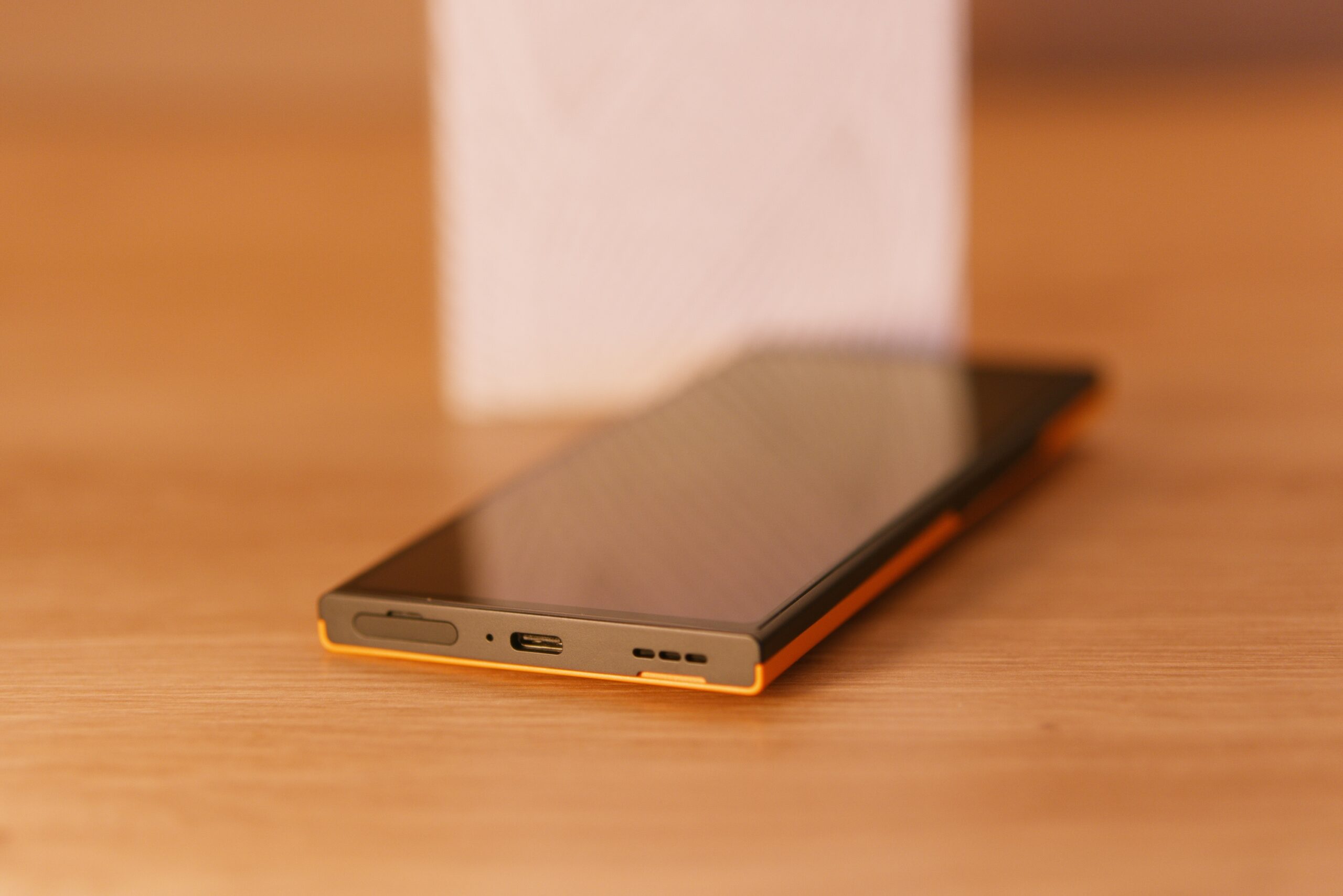 Das jolla Phone liegt am Rücken mit ausgeschalteten Display. Auf der Unterseite sieht man v.l.n.r SIM/MSD Tray, Mikrofon, USB-C, Lautsprecher
