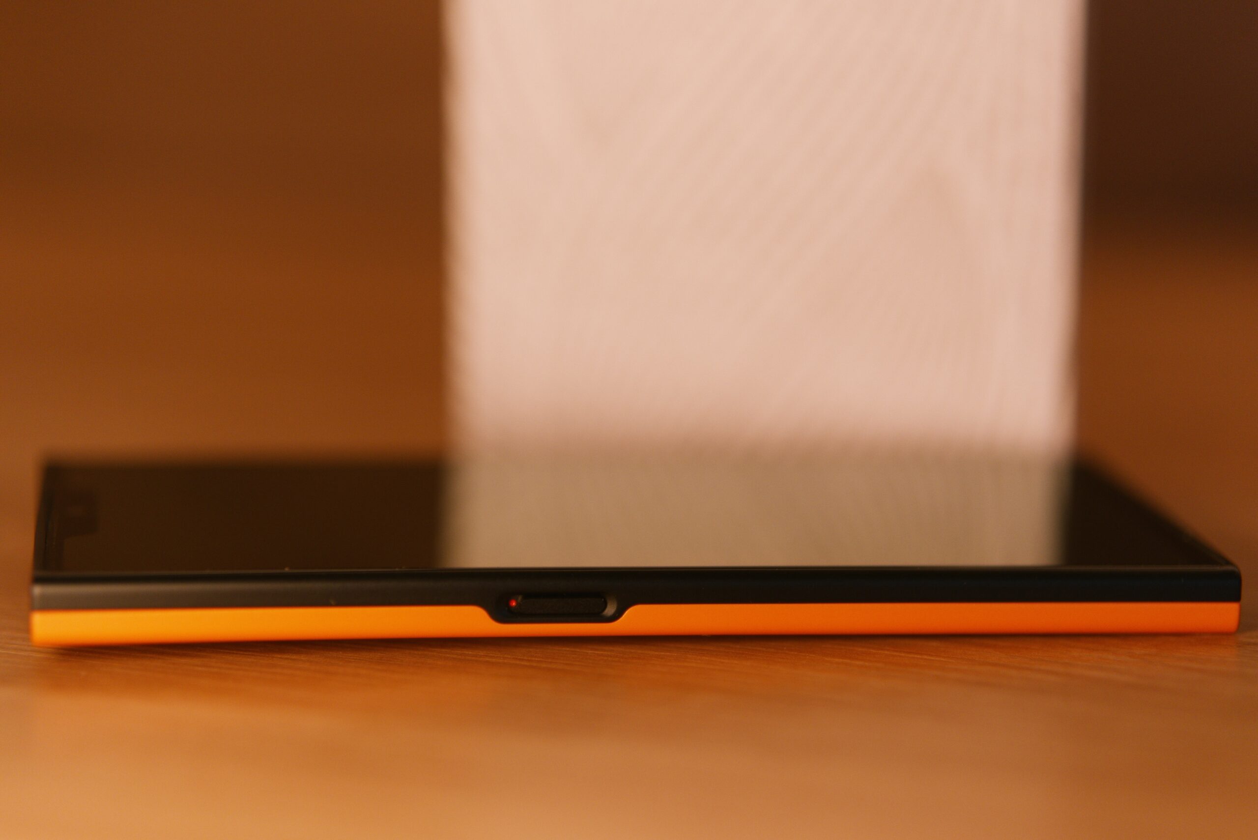 Das jolla Phone liegt am Rücken mit ausgeschalteten Display von Seitlicher Ansicht (Links). Man sieht einen Schalter den Privacy Switch